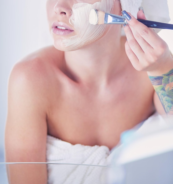 A picture of a young woman applying face powder in the bathroom