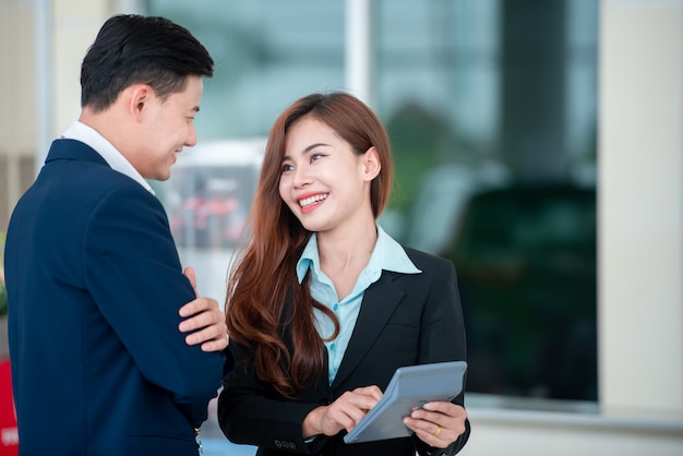 Pictures of Asian customers and happy salespeople who buy new cars that enter into sales agreements with car dealers at car dealers.