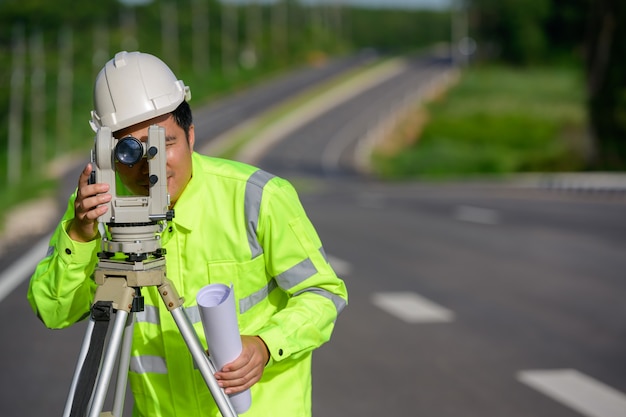 調査作業を行っている土木技師の写真セオドライトを使用して、土地の座標を測定しました。道路の建設現場で屋外セオドライトに立っています。