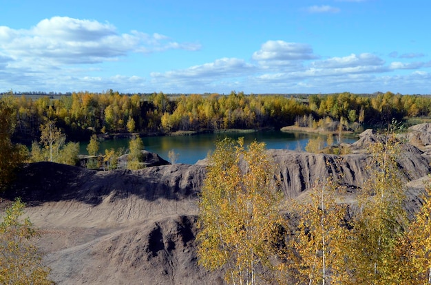 Picturesque autumnal landscape with yellow trees, blue lake, rocky mountains. Lovely mountain view