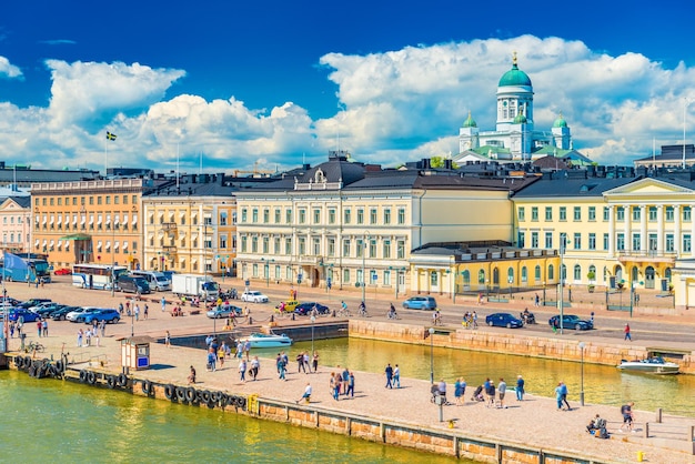 Picturesque cityscape of Helsinki, Finland. View of the city center with historical buildings, The Cathedral, beautiful clouds in the blue sky and people walking along an embankment