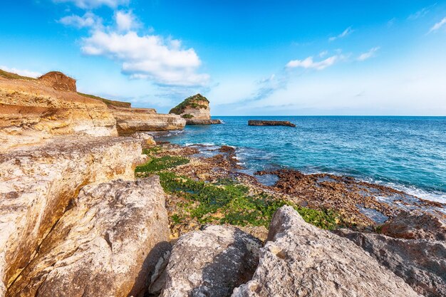 Foto pittoresco paesaggio marino con scogliere rocciose bianche baia di mare isolotti e faraglioni vicino alla spiaggia spiaggia della punticeddha salento costa del mare adriatico puglia italia