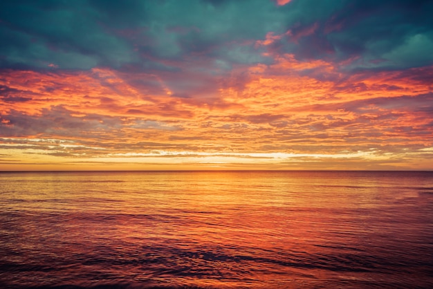 Picturesque sunrise over the sea. Dramatic sky colored in orange and red.