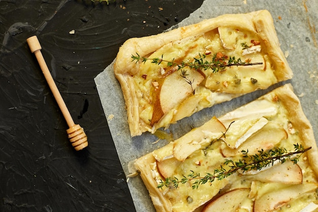 Pie baked in puff pastry with gorgonzola cheese and pears on black table