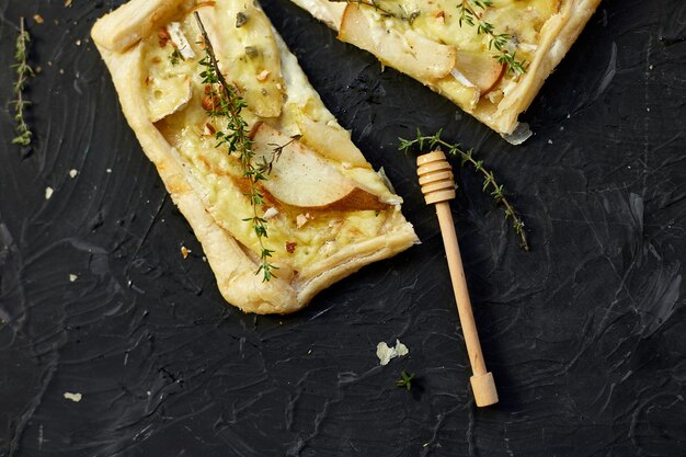 Pie baked in puff pastry with gorgonzola cheese and pears on black table