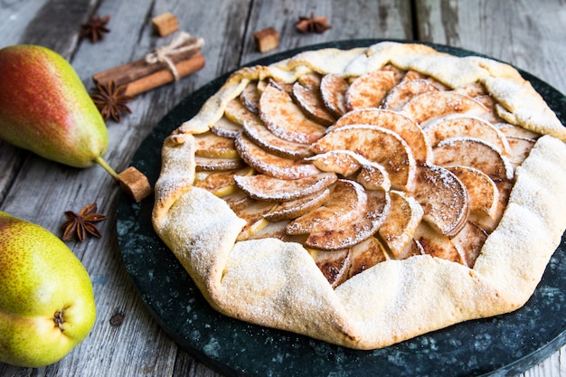 Pie with apples, pears and cinnamon on an old wooden background