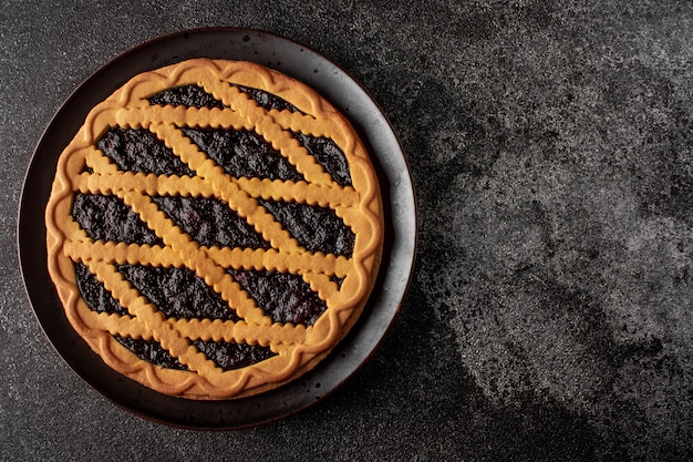 pie with black currant on black plate