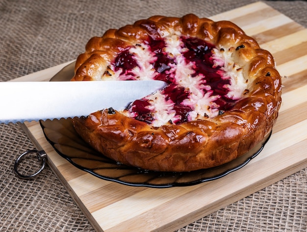 Pie with cherries and cottage cheese on a wooden Board and a knife.