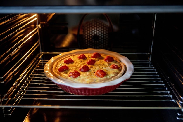 Photo pie with chicken and tomatoes is on a baking sheet in the oven quiche loren