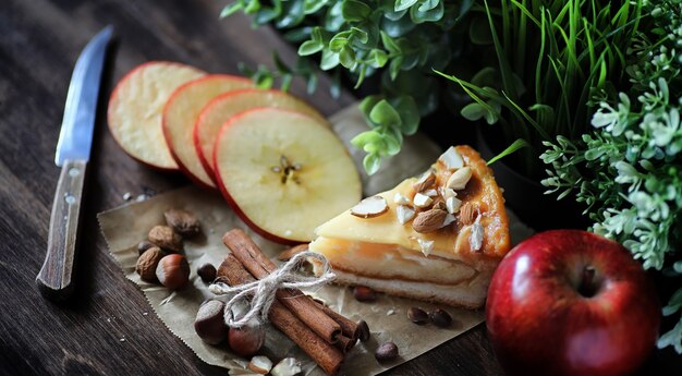 Torta con cannella e mele su un tavolo di legno. pasta fresca con bastoncini di cannella con noci e zucchero a velo. panino con noci e cannella sul tavolo.