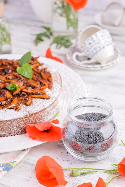 Pie with poppy seeds on a white background. Homemade pastries and red flowers