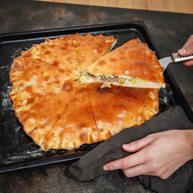 Pie with potato and saury on a baking sheet