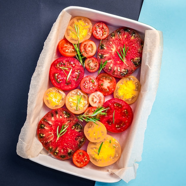 Pie with tomatoes, olive oil, Parmesan cheese and rosemary on parchment paper into ceramic dish