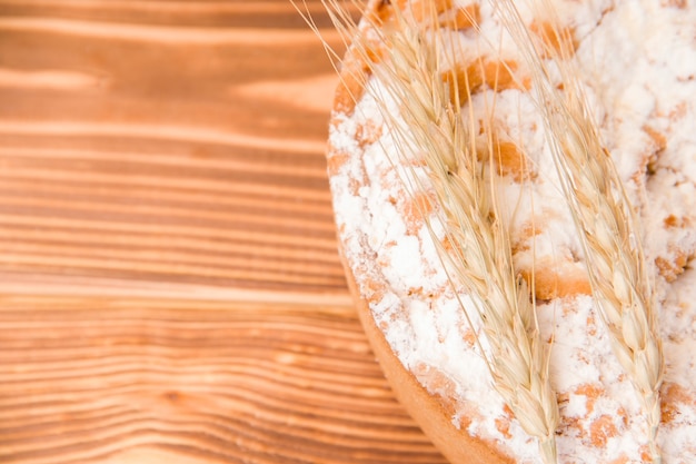 Pie on a wooden table decorated with an ear of wheat