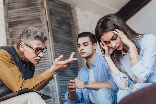 Photo piece of advice. nice pleasant young couple looking at their therapist and listening to her while trying to cope with their problems