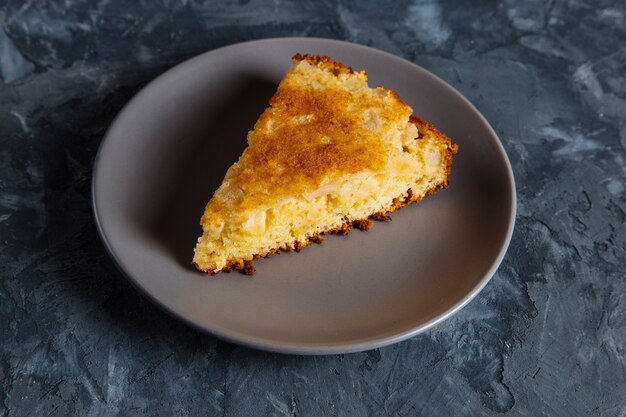 A piece of apple pie on a gray plate