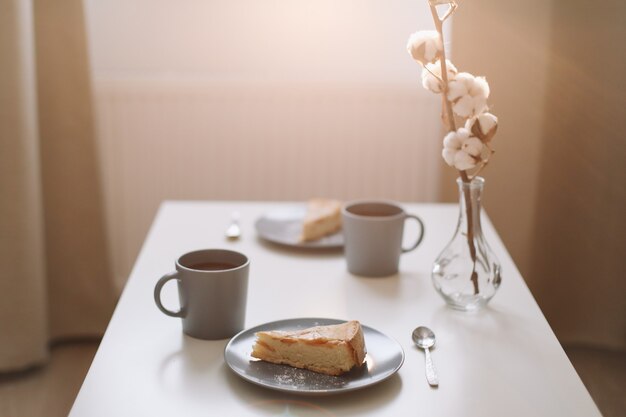 piece of apple pie on plate with cup of coffee on white table