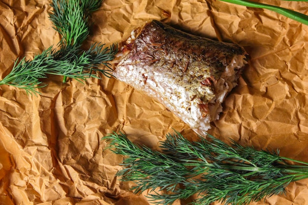 A piece of baked fish on parchment paper. Fried fish with herbs