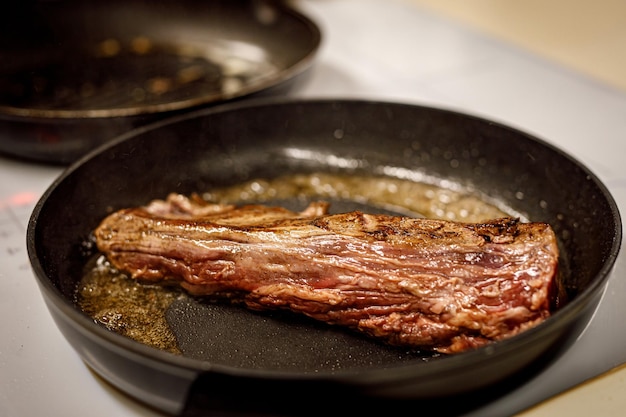 A piece of beef is fried in a pan