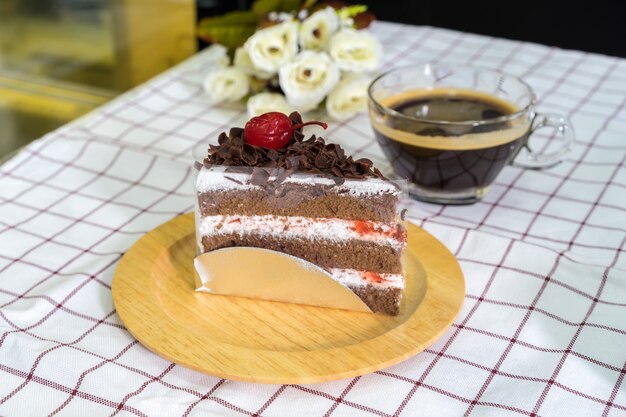 Piece of Black forest cake on wooden plate and coffee cup 