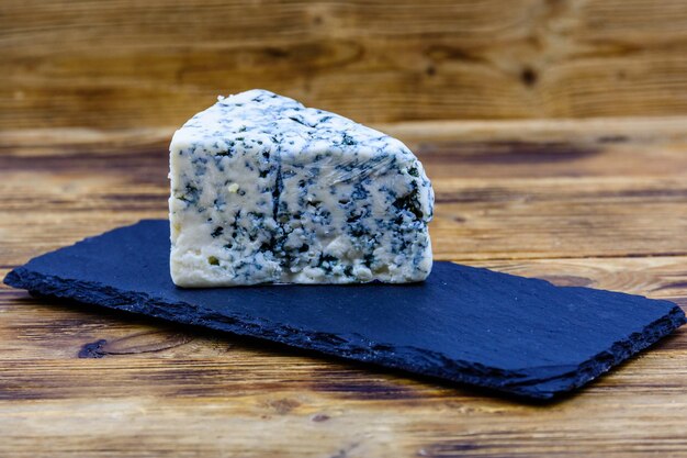 Piece of the blue cheese with mold on slate board