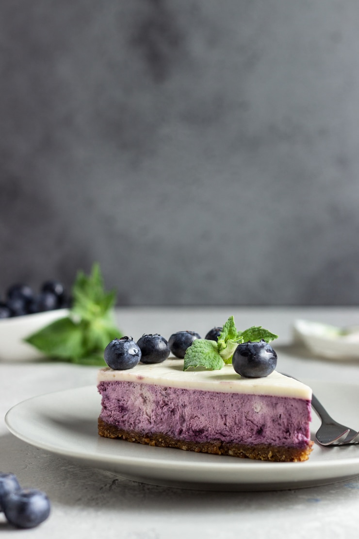 Фотография кусочек черничного чизкейка, свежей черники и мяты