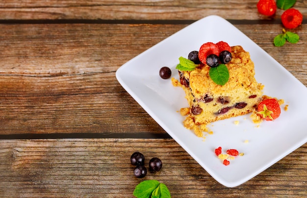 Piece of blueberry pie on white plate on wooden surface