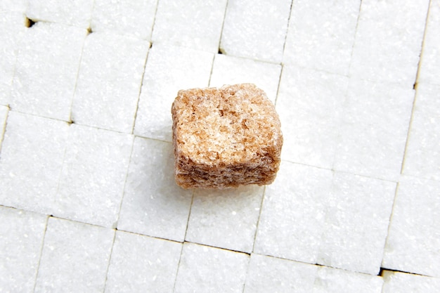 Piece brown cane unrefined sugar laying on white sugar cubes