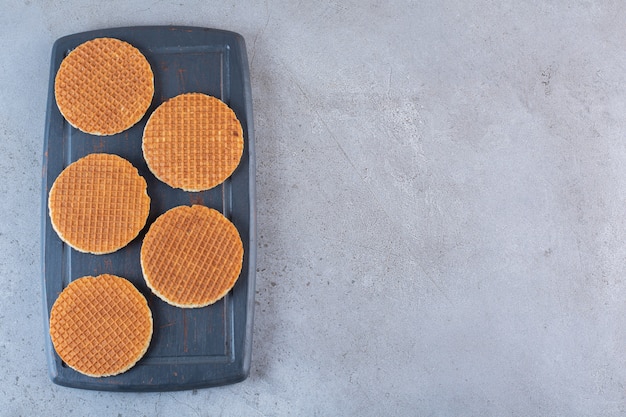 Piece of brown homemade stroopwaffle snacks in a wooden board.