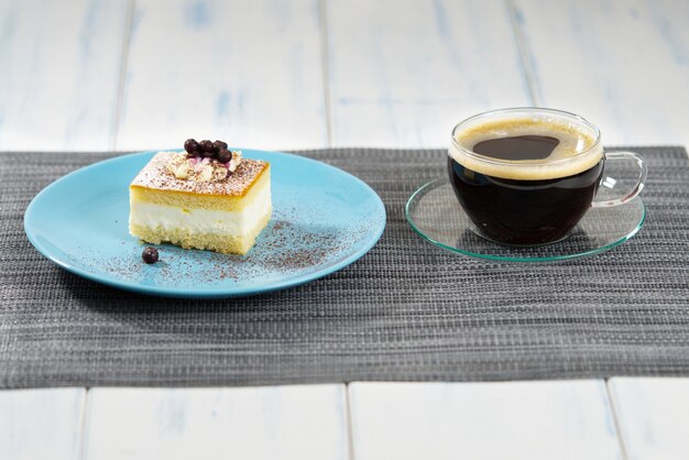 A piece of cake on a blue plate and a cup of coffee