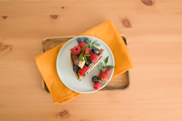 A piece of cake decorated with berries on a plate, top view