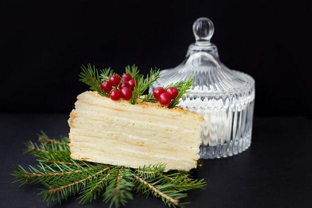 Piece of cake decorated with branches and berries and marshmallows