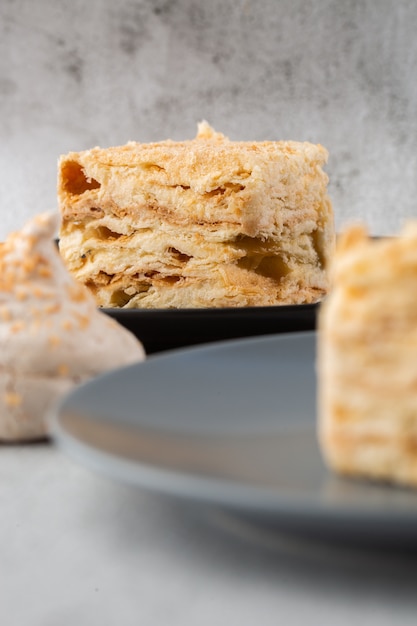 Pezzo di dolce napoleone sul piatto blu su fondo di marmo, vista da vicino. dolce tradizionale millefoglie con pasta sfoglia e crema pasticcera, copia spazio. foto verticale. foto per menu da forno.