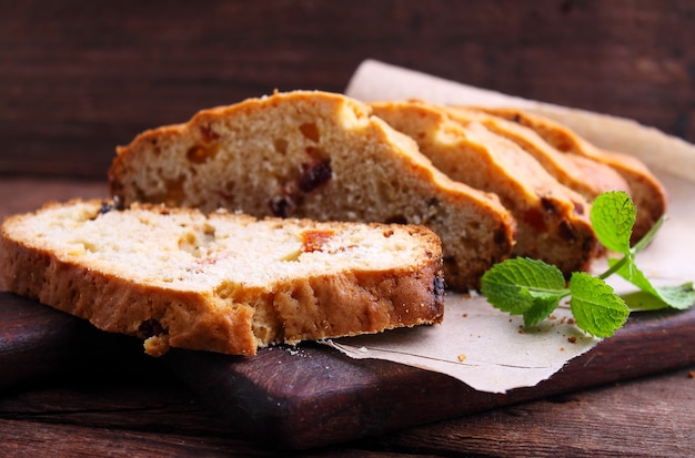 Un pezzo di torta con uvetta e frutta candita su un piatto bianco su sfondo blu