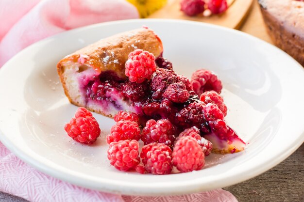 A piece of cake with raspberries and fresh berries on the plate