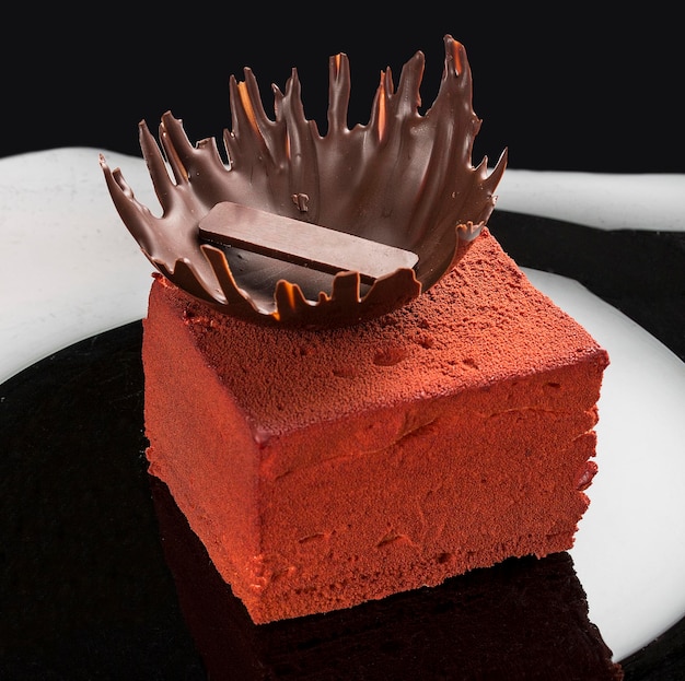 Piece of cake with souffle Bird's milk biscuit mousse and dark chocolate on dark background