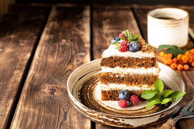 A piece of carrot cake decorated with berries and figs on a wood. Traditional donkey pastries. 