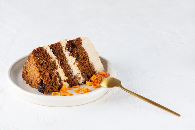 Photo a piece of carrot cake with coconut cream and a spoon on a plate