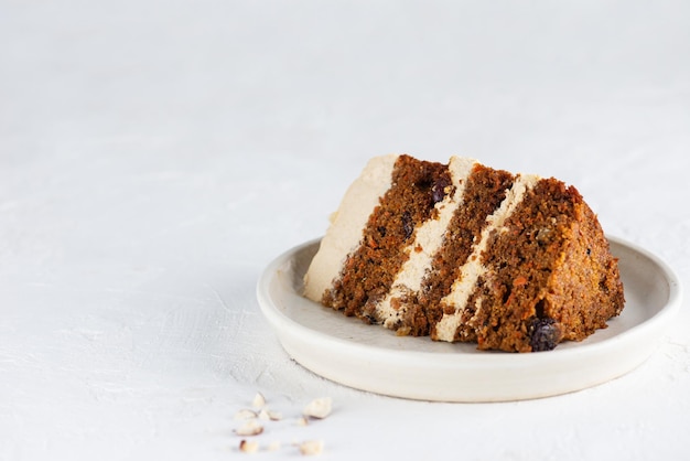 A piece of carrot cake with coconut cream walnuts and spices on a plate