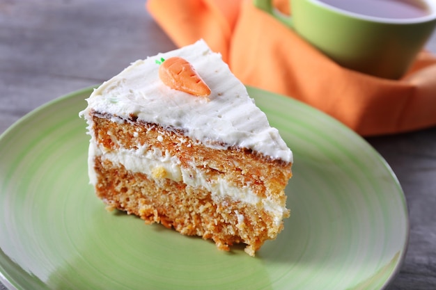 Piece of carrot cake with a cup of tea on wooden table