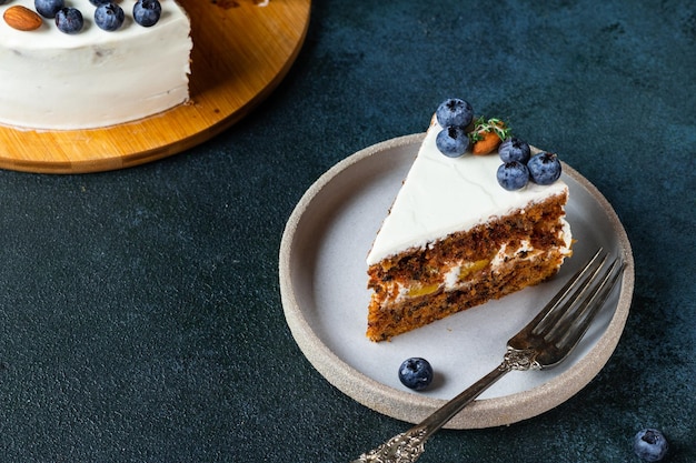 Piece of carrot cake with walnuts and blueberry on dark background. Local food. Traditional american cake. Cake for thanksgiving day. Christmas cake.