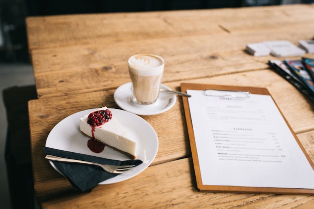 Photo piece of cheesecake and coffee on the table in the coffee house