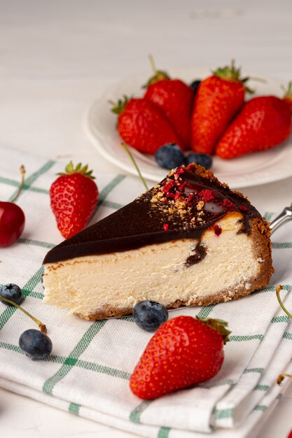 Piece of cheesecake with chocolate top and berries