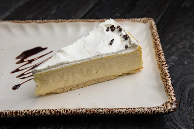 piece of cheesecake with cream and chocolate on a white plate