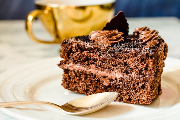 Foto pezzo di torta al cioccolato in un piatto bianco e una tazza di caffè d'oro, primo piano. messa a fuoco selettiva. concetto di inverno natale e capodanno.