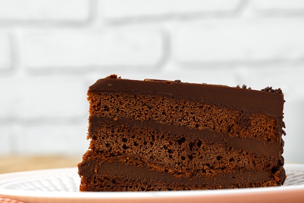 Piece of chocolate cake on white plate on table