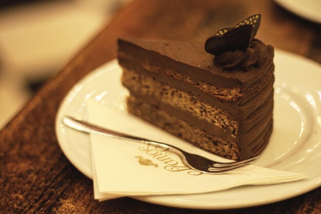 A piece of chocolate cake on a white plate with a fork