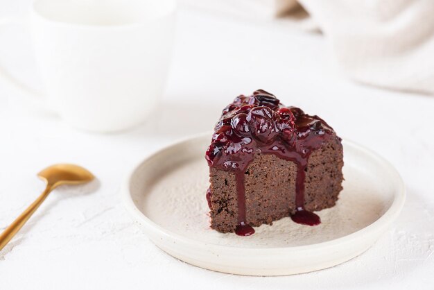 A piece of chocolate cake with black currants on a light background