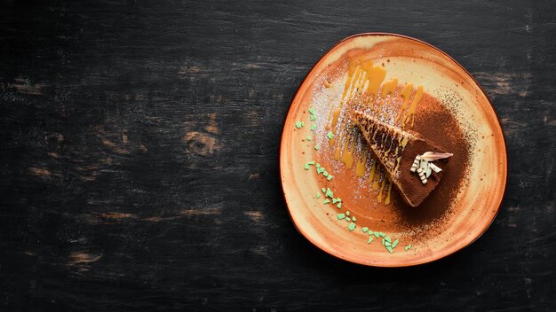 A piece of chocolate cake with caramel Spartacus On a wooden background Top view Free copy space