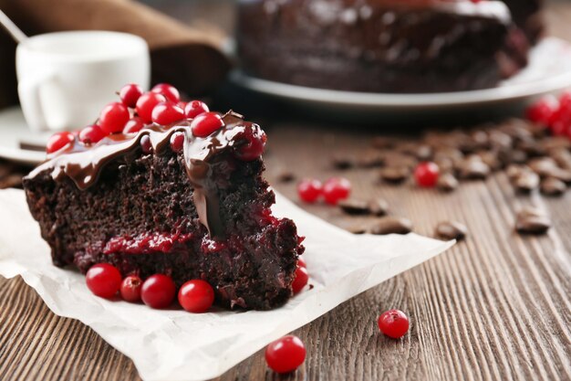 Piece of chocolate cake with cranberries on parchment closeup